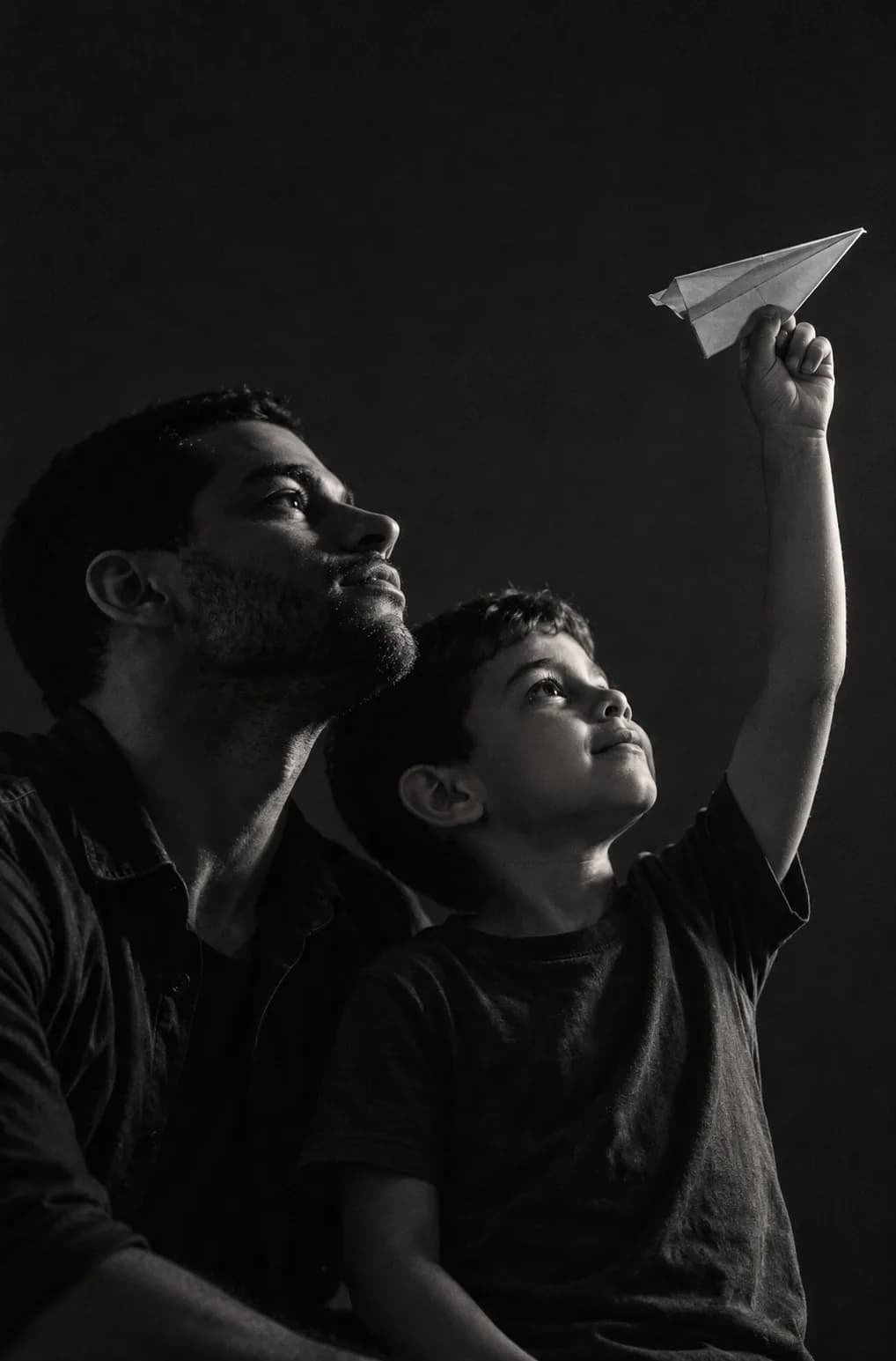 Um pai e o filho olham para o alto; o menino segura um aviãozinho de papel.